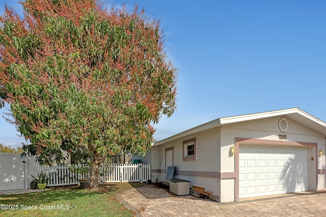 view of property exterior featuring stucco siding, a garage, and fence