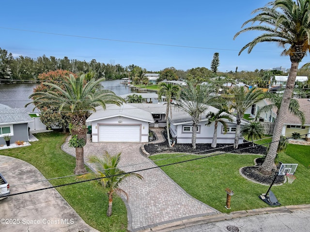 view of front of house featuring a front lawn, fence, a water view, decorative driveway, and an attached garage