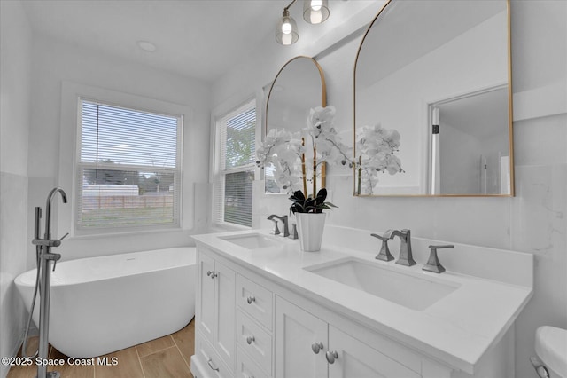 full bath with double vanity, a soaking tub, a sink, and wood finish floors