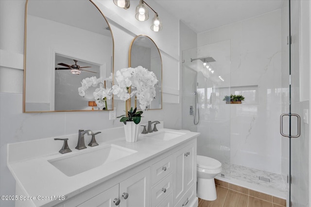 full bathroom with double vanity, a shower stall, toilet, and a sink