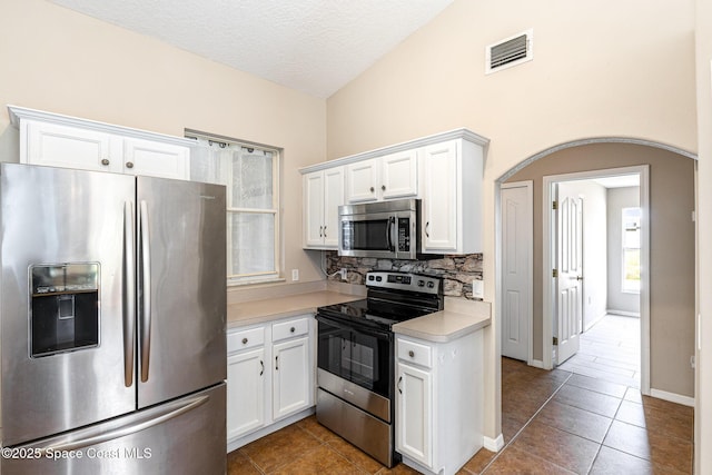 kitchen featuring arched walkways, white cabinets, visible vents, stainless steel appliances, and light countertops