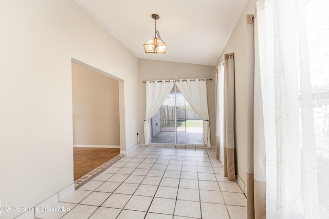 empty room featuring lofted ceiling, light tile patterned floors, baseboards, and an inviting chandelier