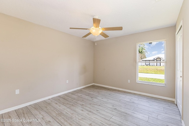 empty room featuring baseboards, ceiling fan, a textured ceiling, and light wood finished floors