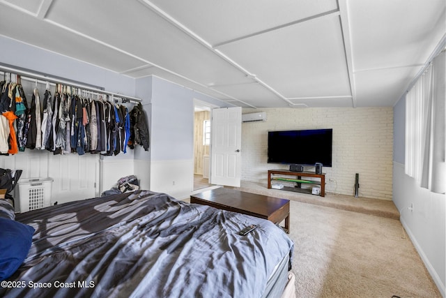 carpeted bedroom featuring brick wall and a wall mounted AC