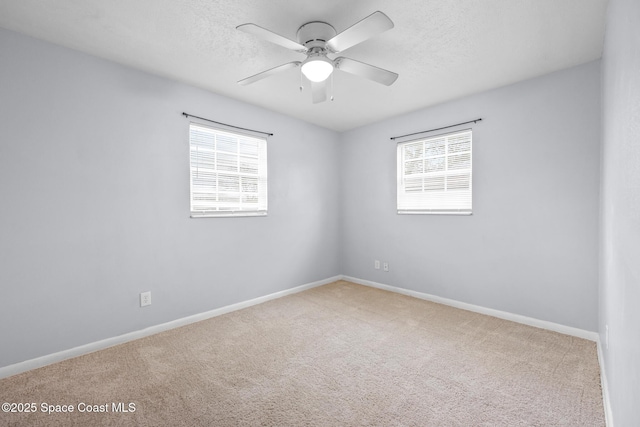 carpeted empty room featuring a ceiling fan, a textured ceiling, and baseboards