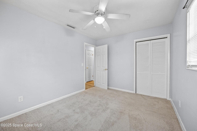 unfurnished bedroom with baseboards, visible vents, ceiling fan, carpet floors, and a closet