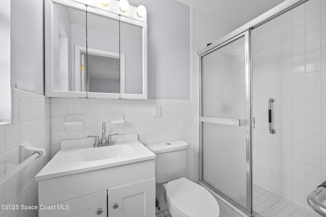 full bathroom featuring toilet, a stall shower, vanity, and tile walls