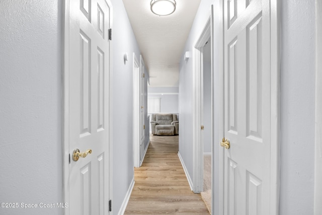 hall with light wood-style flooring and baseboards