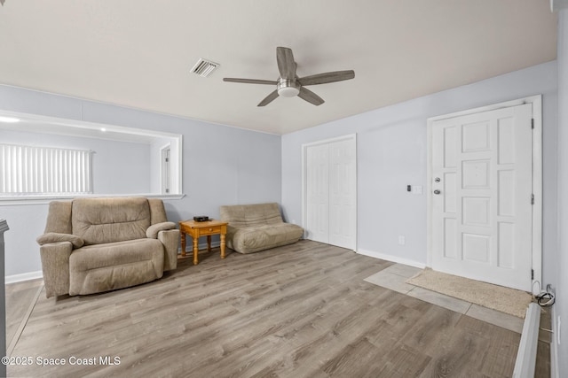 living area featuring a ceiling fan, wood finished floors, visible vents, and baseboards