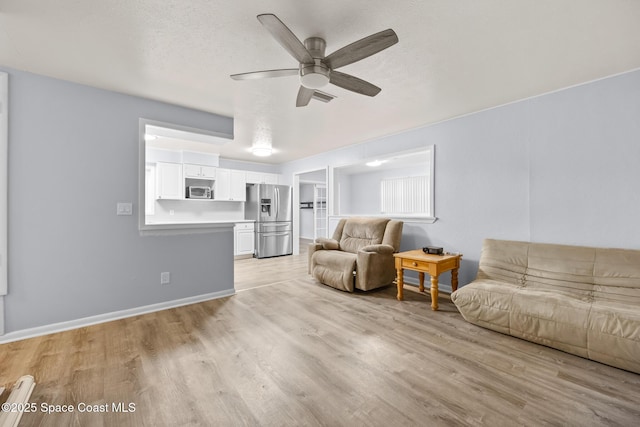 living room featuring light wood-style floors, visible vents, ceiling fan, and a textured ceiling