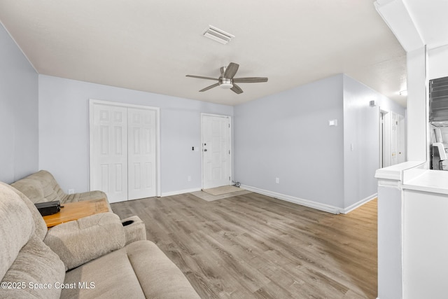 living area featuring light wood-style flooring, a ceiling fan, visible vents, and baseboards