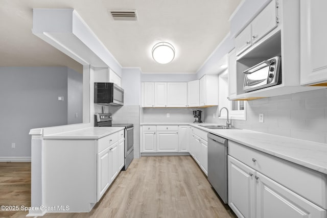 kitchen featuring visible vents, appliances with stainless steel finishes, white cabinets, and a sink