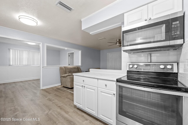 kitchen with visible vents, white cabinets, appliances with stainless steel finishes, light countertops, and light wood-style floors