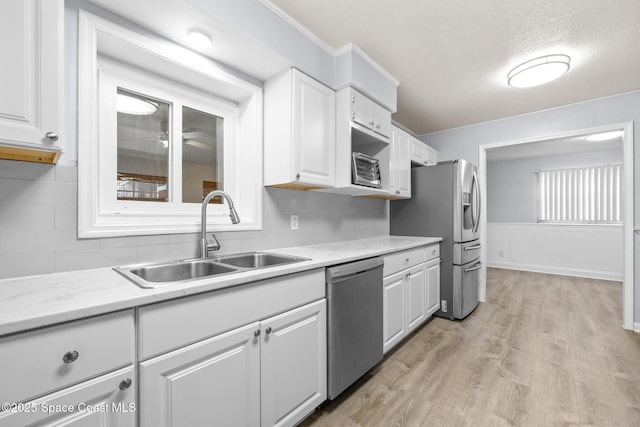 kitchen featuring stainless steel appliances, a sink, white cabinetry, and light wood-style floors