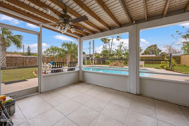 unfurnished sunroom with wood ceiling, vaulted ceiling with beams, a ceiling fan, and a healthy amount of sunlight