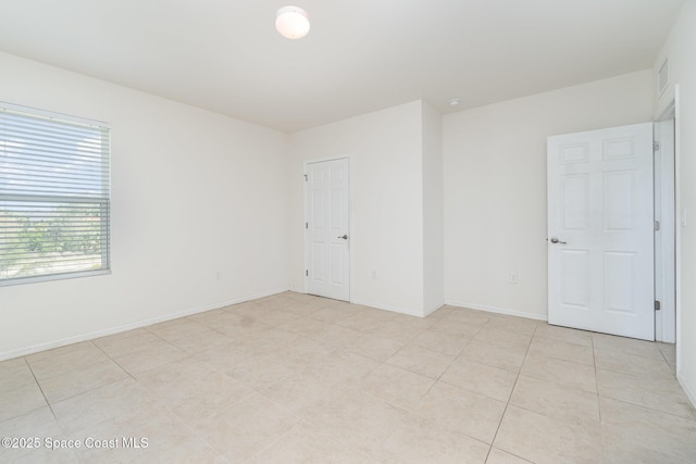 empty room with light tile patterned floors and baseboards