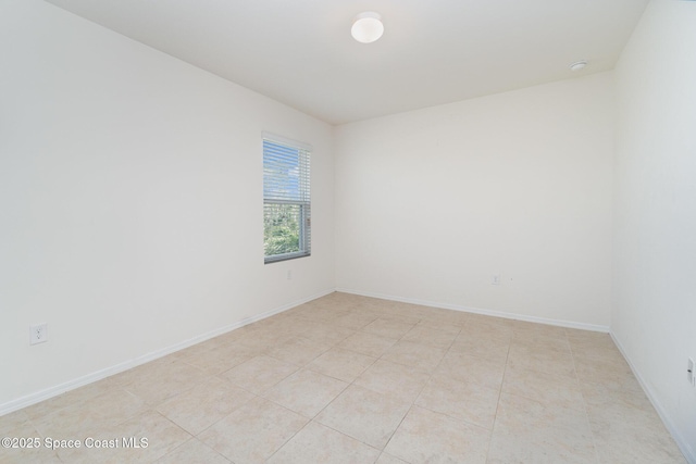 spare room with baseboards and light tile patterned floors