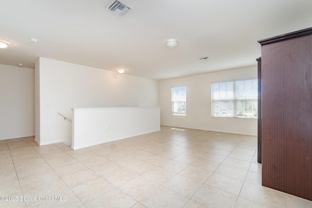 empty room featuring light tile patterned flooring, visible vents, and baseboards