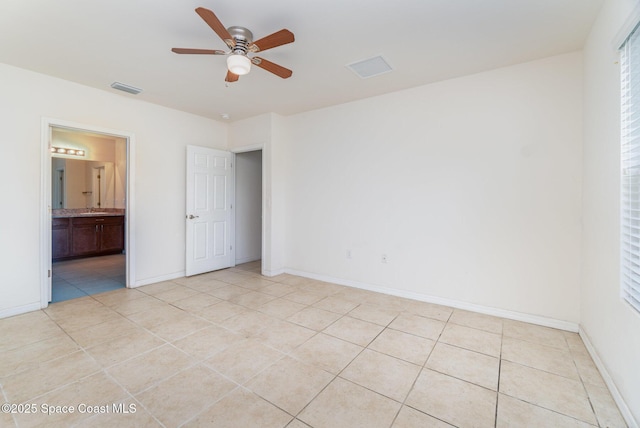 unfurnished bedroom with ensuite bath, light tile patterned floors, baseboards, and visible vents