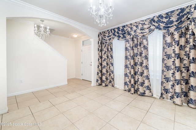 unfurnished room featuring arched walkways, light tile patterned floors, baseboards, an inviting chandelier, and crown molding