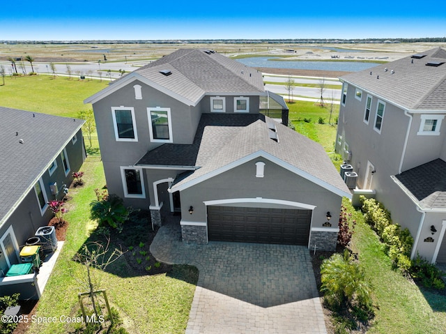 view of front of house featuring a garage, a shingled roof, stone siding, decorative driveway, and stucco siding