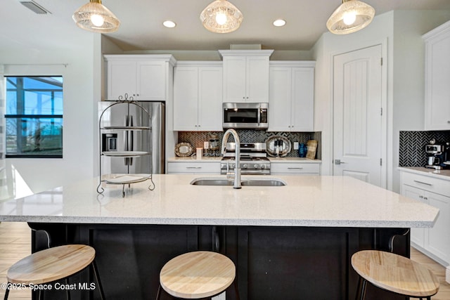 kitchen featuring appliances with stainless steel finishes, white cabinets, visible vents, and a sink