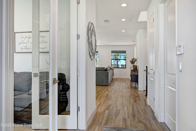 corridor with baseboards, wood finished floors, visible vents, and recessed lighting