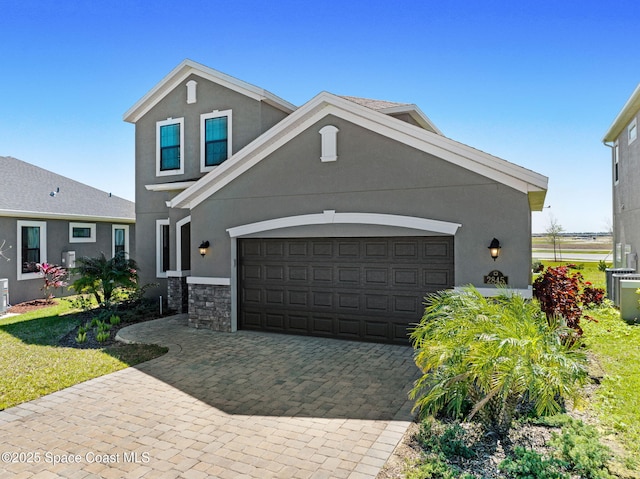 view of front of property with stone siding, decorative driveway, and stucco siding