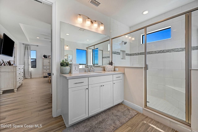 full bath with a stall shower, visible vents, vanity, and wood finished floors