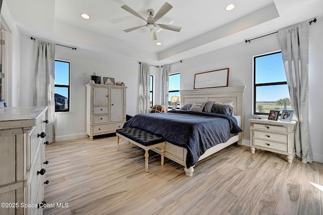 bedroom featuring a tray ceiling and light wood finished floors