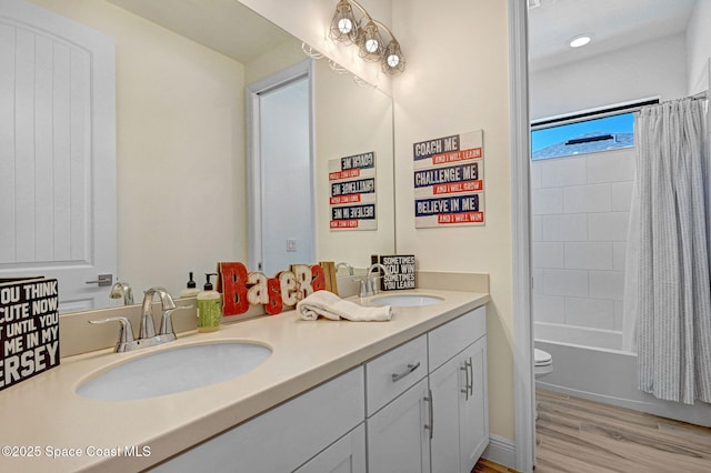 bathroom featuring double vanity, wood finished floors, a sink, and shower / bath combo with shower curtain