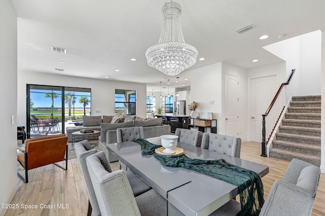 dining area featuring stairway, light wood-style flooring, visible vents, and a chandelier