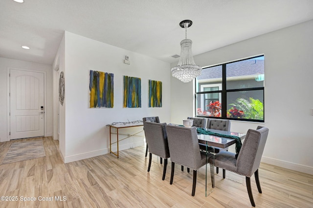 dining room featuring baseboards, light wood finished floors, visible vents, and an inviting chandelier