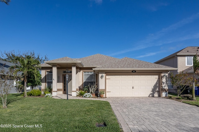 view of front facade featuring an attached garage, a front yard, decorative driveway, and stucco siding