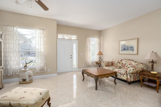 living area with a ceiling fan and baseboards