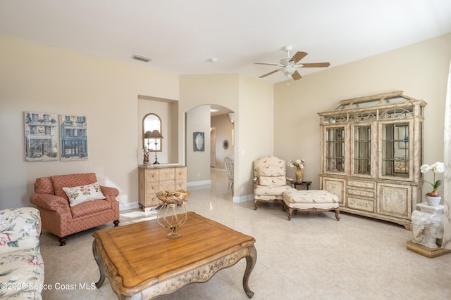 living area featuring arched walkways, baseboards, visible vents, and a ceiling fan