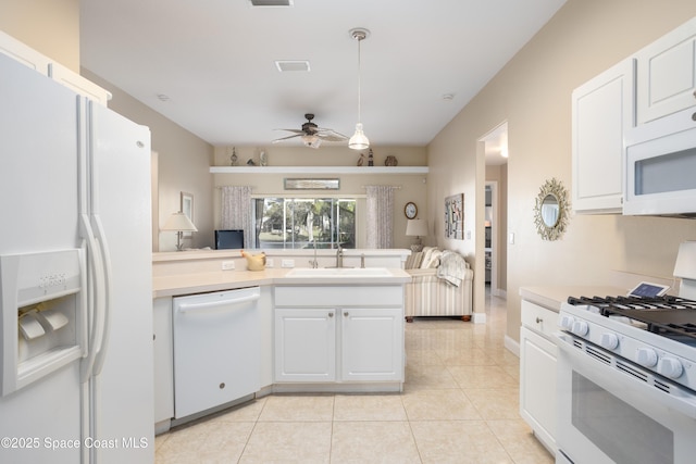 kitchen featuring hanging light fixtures, white appliances, light countertops, and a sink