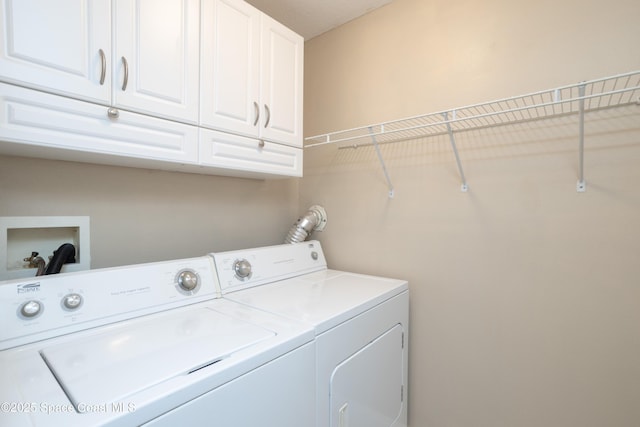 clothes washing area featuring washing machine and clothes dryer and cabinet space