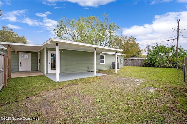 rear view of property featuring central air condition unit, a patio area, a fenced backyard, and a yard