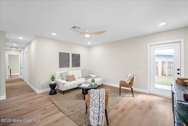 living area with light wood-style flooring, visible vents, and baseboards