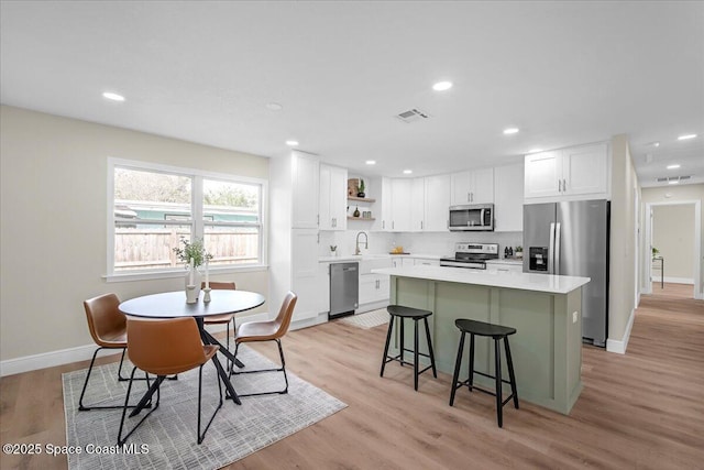 kitchen featuring appliances with stainless steel finishes, white cabinets, light countertops, and visible vents