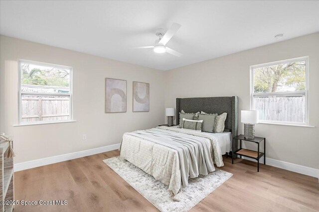 bedroom with light wood-style floors, baseboards, and a ceiling fan