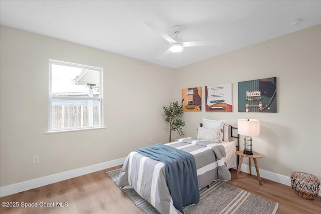 bedroom featuring a ceiling fan, baseboards, and wood finished floors