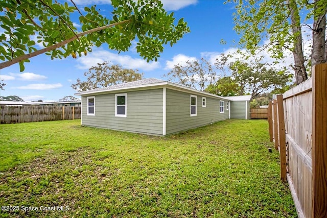 rear view of house with a fenced backyard and a yard