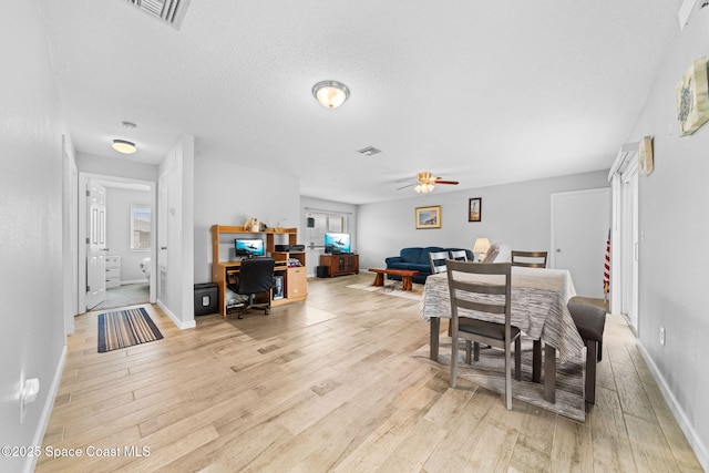 dining room with visible vents, light wood-style floors, ceiling fan, a textured ceiling, and baseboards