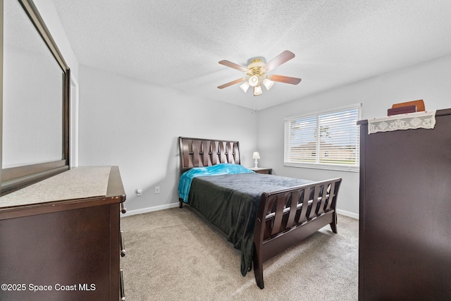 bedroom featuring a ceiling fan, light carpet, a textured ceiling, and baseboards