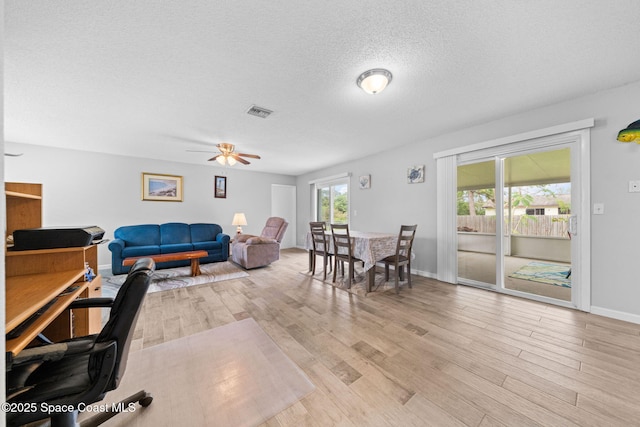 interior space featuring a textured ceiling, light wood-style flooring, visible vents, and baseboards