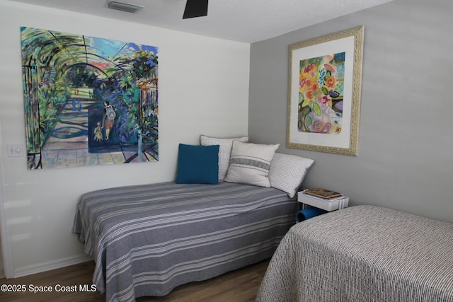 bedroom with dark wood-style floors, visible vents, and baseboards
