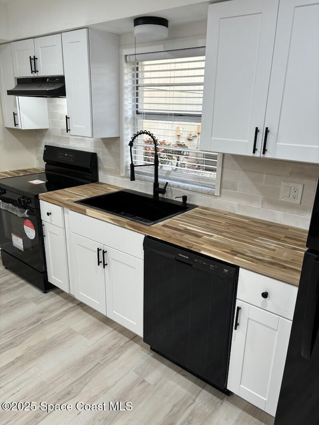 kitchen featuring tasteful backsplash, white cabinetry, a sink, under cabinet range hood, and black appliances