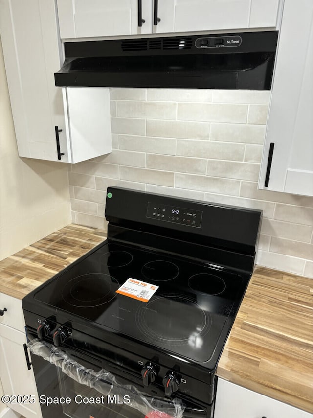 interior details with under cabinet range hood, decorative backsplash, white cabinetry, and black electric range oven